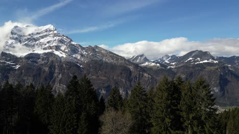 Beautiful-aerial-drone-forward-moving-shot-of-snow-covered-mountain-peaks-alongside-a-valley-in-Fronalpstock-Switzerland-Glarus-on-a-sunny-day