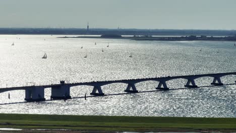 Long-lens-drone-shot-of-the-Zeeland-bridge-back-lit-showing-sailboats-in-the-distance