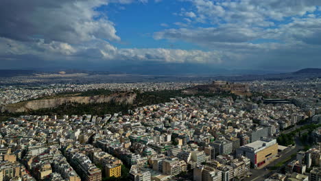 Aerial-drone-shot-over-Acropolis-city-of-Athens-parthenon,-surrounded-by-residential-buildings-in-Athens,-Greece-on-a-cloudy-day