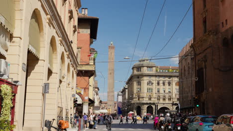 Belebte-Straßenszene-In-Bologna-Mit-Historischem-Garisenda-Turm-An-Einem-Sonnigen-Nachmittag