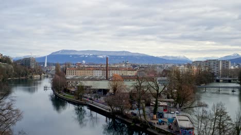 Un-Panorama-De-Una-Zona-Industrial-De-La-Ciudad-De-Ginebra,-Que-Muestra-En-Primer-Plano-El-Río-Ródano-Y-Al-Fondo-El-Jet-D&#39;eau-Y-Los-Alpes