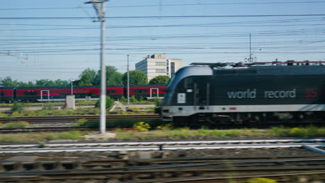 Passing-by-red-passenger-train-moving-through-suburban-landscape-in-Italy