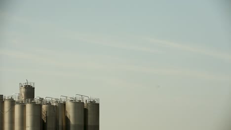 Silos-Contra-Un-Cielo-Pálido-Al-Amanecer,-Sutil-Encanto-Industrial-Con-Suave-Iluminación-Natural