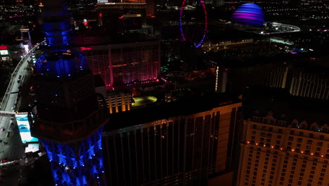 Drone-shot-around-the-Eiffel-tower,-revealing-the-illuminated-Strip-and-Bellagio-fountains,-night-in-Las-Vegas