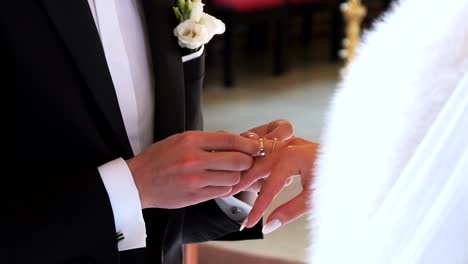 During-the-wedding-ceremony,-the-groom-puts-a-gold-ring-on-the-bride's-finger