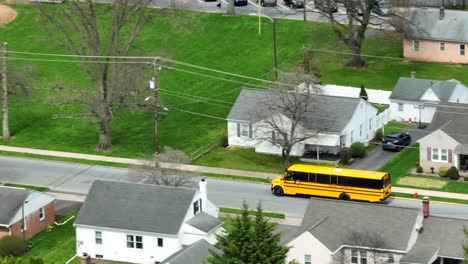 Yellow-American-school-bus-driving-on-rural-road-of-American-town