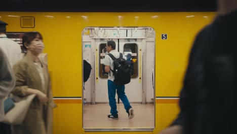 Travelers-Walking-At-Subway-Station-In-Tokyo,-Japan-With-Passenger-Train-In-Background