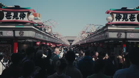 Crowded-Nakamise-dori-Street-With-White-Sakura-Blossoms-In-Spring-In-Asakusa,-Tokyo,-Japan