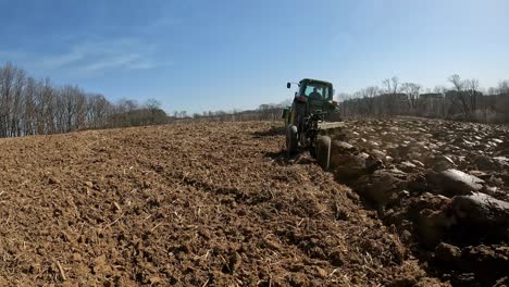 Ein-John-Deere-Traktor-Mit-Angebautem-Lader-Schleppt-Einen-Pflug,-Um-Den-Boden-Umzugraben,-Als-Ersten-Schritt-Bei-Der-Vorbereitung-Des-Feldes-Für-Die-Frühjahrsbepflanzung