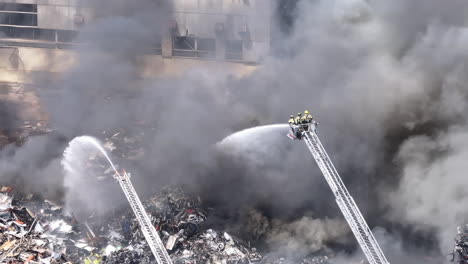Slow-motion-aerial-footage-of-firefighters-fighting-a-large-scrap-metal-fire-in-Chattanooga,-TN