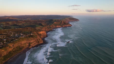 Vista-Aérea-De-La-Costa-De-La-Comunidad-Costera-De-Muriwai-Al-Atardecer-En-Auckland,-Nueva-Zelanda