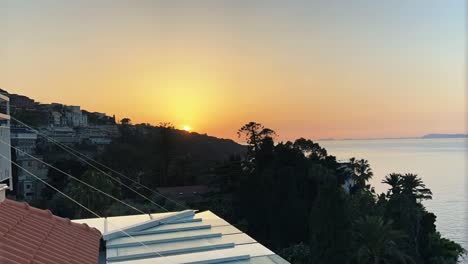 Zeitraffer-Des-Sonnenuntergangs-über-Den-Atemberaubenden-Küstenklippen-Von-Sorrento-Nahe-Der-Amalfiküste,-Italien,-Während-Die-Feurige-Sonne-Unter-Den-Horizont-Sinkt-Und-Den-Himmel-In-Leuchtende-Orangetöne-Taucht