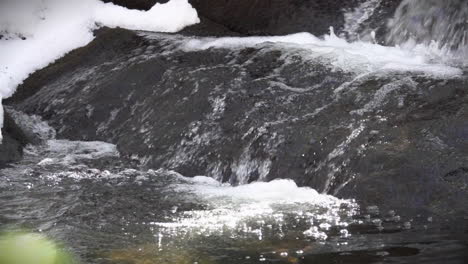 Close-up-of-refreshing-glacial-melt-water-flowing-over-a-rock-in-slow-motion
