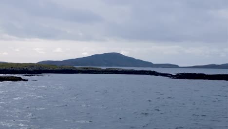 Scenic-view-of-remote,-rugged-and-rocky-islands-with-birds-traveling-on-passenger-ferry-from-Barra-to-South-Uist-in-the-Outer-Hebrides-of-Scotland-UK