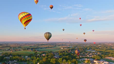 Hot-air-balloons-soar-over-a-tranquil-rural-setting,-bathed-in-the-warm-glow-of-morning-light