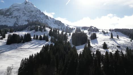 Luftaufnahme-Einer-Drohne-Von-Links-Nach-Rechts-über-Einen-Schneebedeckten-Berghang-Mit-Bergen-Im-Hintergrund-An-Einem-Sonnigen-Tag