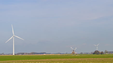 Windturbines-and-an-old-windmill-in-an-agricultural-field-in-the-Netherlands,-Europe