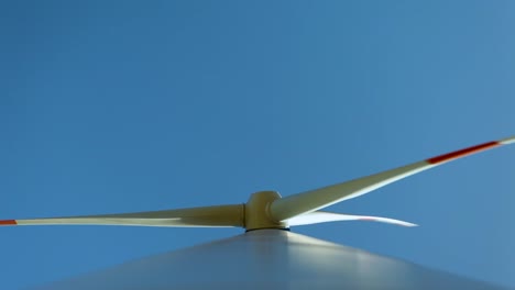 Dynamic-close-up-of-a-spinning-wind-turbine-blade-against-a-clear-blue-sky