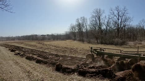 Tractor-and-plow-pass-by-while-preparing-the-field-for-planting-in-early-spring