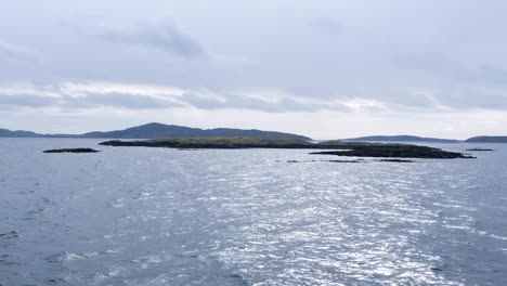 Vorbeiblick-Von-Der-Passagierfähre-Auf-Schroffe,-Felsige-Und-Kleine-Inseln-Mit-Vögeln-Und-South-Uist-In-Der-Ferne-In-Den-Äußeren-Hebriden-Von-Schottland,-Vereinigtes-Königreich