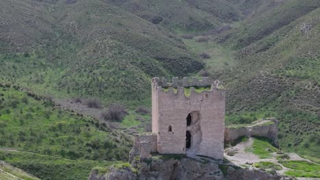 drone-flight-over-the-9th-century-castle-of-the-ear,-focusing-mainly-on-its-keep,-following-it-with-a-panning-of-the-camera-with-a-background-of-slopes-with-paths-and-vegetation-filmed-in-70mm