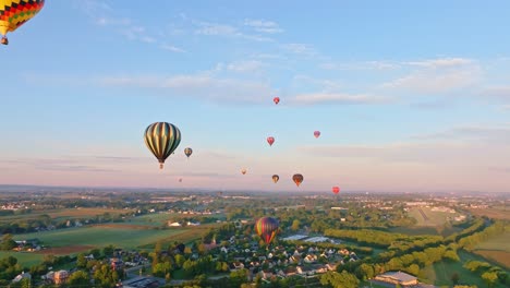 Heißluftballons-Schweben-über-Einer-Ruhigen-Ländlichen-Umgebung,-Getaucht-In-Das-Warme-Licht-Des-Morgenlichts