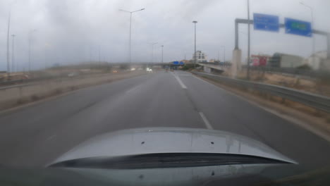 Un-Hiperlapso-Dinámico-De-Una-Cámara-Deportiva-Montada-En-El-Techo-De-Un-Automóvil,-Conduciendo-A-Través-De-Grecia-Hacia-Atenas-Por-Una-Autopista,-Capturando-Un-Viaje-A-Través-De-Un-Túnel-Iluminado-Bajo-La-Lluvia