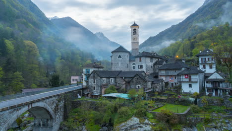 Alte-Kirche-Zwischen-Wäldern-Und-Bergen-Mit-Einer-Steinbrücke-In-Der-Abenddämmerung-Mit-Nebel