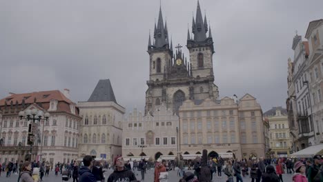 Crowded-Old-Town-Square-in-Prague-with-tourists-and-historic-architecture,-cloudy-day,-tilt-down-shot