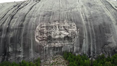 cinematic-aerial-pull-in-reveal-shot-of-an-ancient-confederate-carving-on-a-large-stone-face-in-the-countryside-in-georgia-during-a-hot-and-sunny-day-in-america