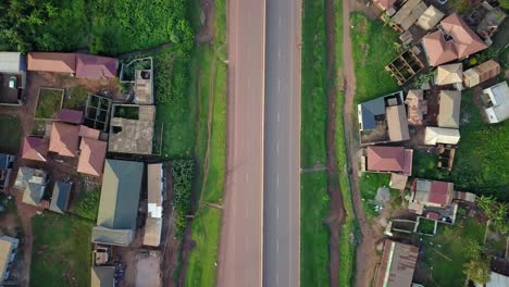 Draufsicht-Auf-Häuser-Entlang-Der-Kampala-Entebbe-Schnellstraße-Mit-Fahrenden-Fahrzeugen-In-Kampala,-Uganda