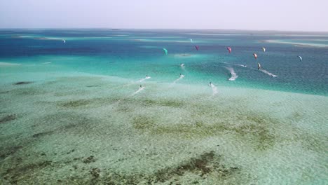 Kite-surfers-gliding-over-the-clear-waters-at-cayo-vapor,-vibrant-aquatic-scene,-aerial-view