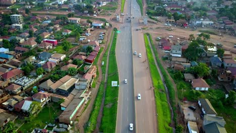 Transporte-Terrestre-Circulando-Por-La-Autopista-A-Través-De-Casas-En-Kampala,-Uganda