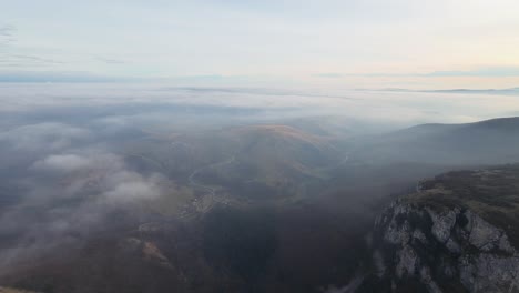 Luftaufnahme-Einer-Nebligen-Berglandschaft-Mit-Sichtbaren-Tälern-Und-Bewaldeten-Bergrücken-Unter-Einem-Sanften,-Wolkigen-Himmel