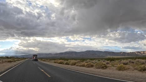 Empty-highway-with-a-view-of-Tehachapi-mountains-under-a-stormy-sky,-timelapse-from-a-moving-vehicle