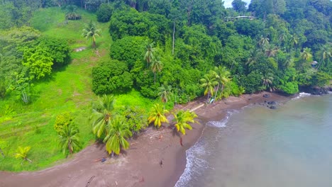 Eine-Person,-Die-In-Der-Regenzeit-An-Einem-Leeren-Strand-In-Drake-Bay,-Costa-Rica,-Neben-Einem-Gesunden-Grünen-Palmendschungel-Entlang-Läuft