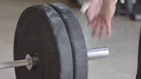 Adding-weights-to-barbell-for-weightlifting-workout-in-gym,-telephoto