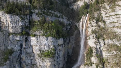 Drone-view-of-famous-Seerenbachfälle-waterfall-during-sunny-day-in-Amden,-Switzerland
