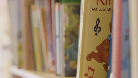 Close-up-of-colorful-children's-books-on-a-shelf-in-a-library,-focus-on-spine-titles