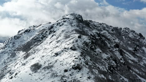Schneebedeckter-Berggipfel-Unter-Einem-Wolkigen-Himmel,-Der-Zerklüftetes-Gelände-Und-Natürliche-Schönheit-Zeigt,-Luftaufnahme