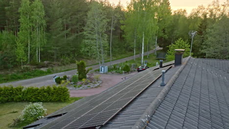 AERIAL:-Sunlight-generator-modules-on-a-ecologic-house-roof,-summer-morning