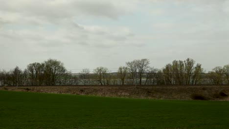 Rote-Lokomotive-Zieht-Güterzug-Durch-Ländliche-Landschaft,-Bewölkter-Himmel