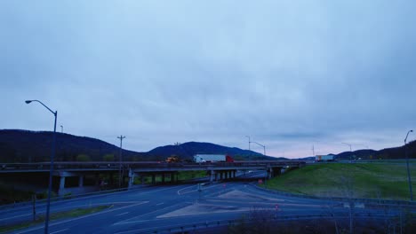 Establisher-aerial-of-multiple-dry-vans-and-reefers-Semi-Trucks-on-Overpass-in-Milesburg,-Pennsylvania,-USA