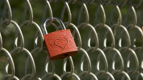 Close-up-of-a-hand-placing-a-heart-engraved-padlock-on-a-chain-link-fence