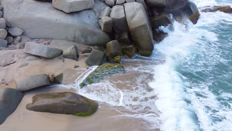 Enormes-Rocas-En-La-Orilla-Rompen-Olas-Rompiendo-En-Una-Playa-Tropical