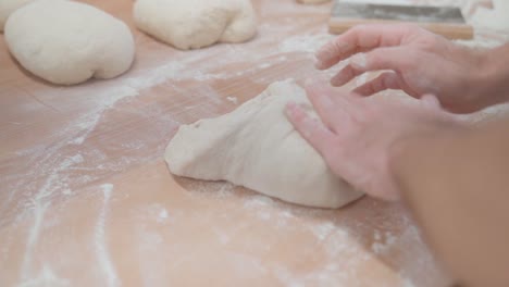 Chef-kneading-a-dough-into-a-bread-loaf-form-on-a-table-in-flour
