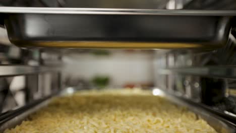 Close-up-of-freshly-cooked-pasta,-sprinkled-with-cheese-in-an-industrial-oven,-shallow-focus
