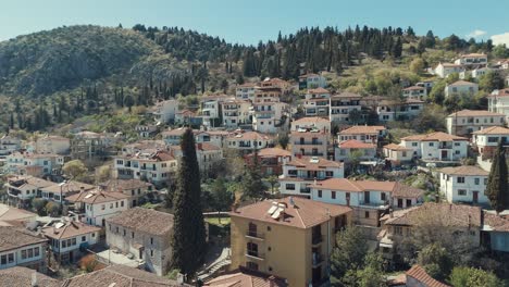 Drone-flying-upwards,-above-a-village-on-a-green-hill-in-Europe,-red-roof-tops,-little-houses,-sunny-weather,-Greece-4K-video