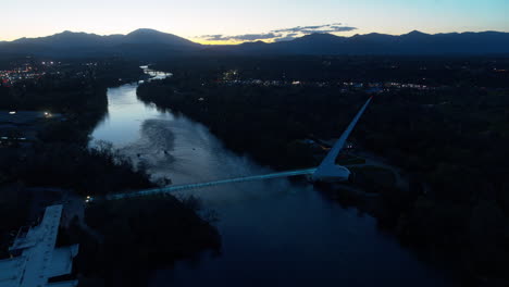 Aerial-footage-rotating-around-the-Sundial-Bridge-in-the-dusk-of-sunset-over-the-Sacramento-River-in-Redding,-California
