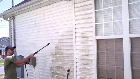 Homeowner-pressure-washing-side-of-house-on-summer-day